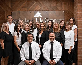 Sutherland Title Company team gathered in front of the office sign